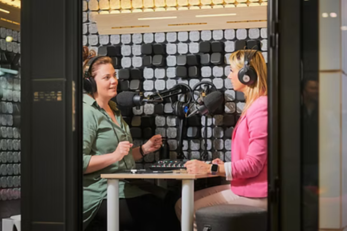 Zwei Frauen sitzen in einem Tonstudio und nehmen einen Podcast auf