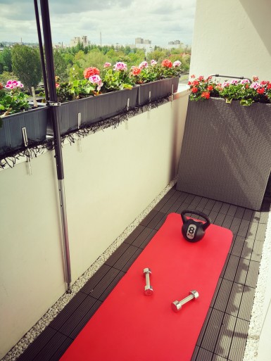 Sports mat with dumbbells on it on the balcony